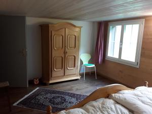 a bedroom with a bed and a cabinet and a window at DesAlpes in Saxeten