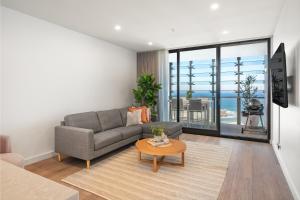 a living room with a couch and a table at 1011 - First Light 2BR with Ocean Views - Prime Location in Newcastle