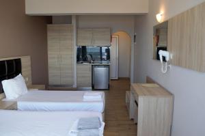 a hotel room with two beds and a kitchen at Coralli Apartments in Pefki