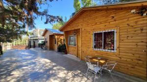 a wooden cabin with chairs and a table on a patio at Cabañas swissminiatur in Cacheuta