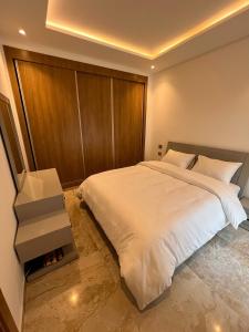 a bedroom with a large white bed with a wooden headboard at Appt lux Hammamet Nabeul in Hammamet Nord