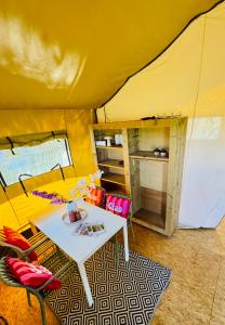 a yellow tent with a table and chairs in a room at Glamping Safaritent 4 persoons in Hindeloopen