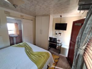 a bedroom with a bed with a green blanket on it at Emakhaya B&B in Mthatha