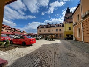 a red car parked in a parking lot next to buildings at Old Town Loft Apartments in Kamianets-Podilskyi