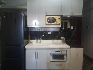 a kitchen with white cabinets and a sink and a microwave at Royal oceancrest mactan in Mactan Island