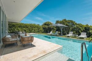 a swimming pool with chairs and an umbrella at Tropical villa w pool & dock access u501 in Barú
