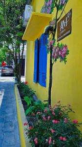 a yellow building with blue shutters and flowers on a street at AM's Home in Ninh Binh +20 photos