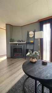 a living room with a table and a fireplace at Geniet van rust en privacy in onze gezellige chalet op familiecamping De Tien Heugten in Drenthe in Schoonloo