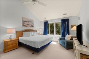 a bedroom with a bed and a tv and a chair at Marsh Breeze Hideaway at Masters Place in Pawleys Island