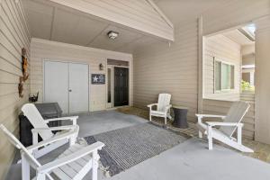 a porch with two white chairs and a door at Marsh Breeze Hideaway at Masters Place in Pawleys Island