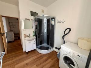 a bathroom with a shower and a washing machine at Mazā Roma in Ventspils