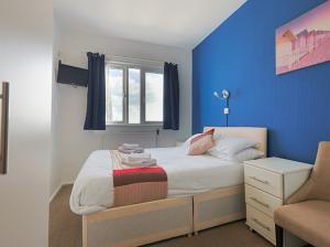 a bedroom with a bed with a blue wall at De L'Etang in Saint Helier Jersey +50 photos