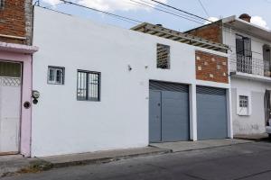 a white house with two garage doors on a street at Casa independencia in Morelia