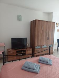 a bedroom with a bed with a tv and wooden cabinets at Studio Apartment Ivo in Cres