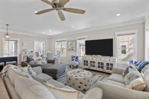 a living room with couches and a flat screen tv at Pool Spa Fire Pit & More at this OKI Escape in Oak Island