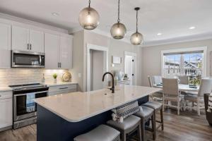 a kitchen with white cabinets and a large island with a sink at Pool Spa Fire Pit & More at this OKI Escape in Oak Island