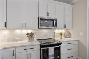 a kitchen with white cabinets and a stove top oven at Pool Spa Fire Pit & More at this OKI Escape in Oak Island