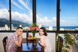 a man and woman sitting at a table in a restaurant at Son Tra Green Hotel & Apartment - near the My Khe beach, Son Tra Peninsula, Linh Ung Pagoda in Danang