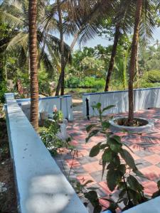 a patio with palm trees and a concrete fence at Samudra Nadi Bliss in Mūlki