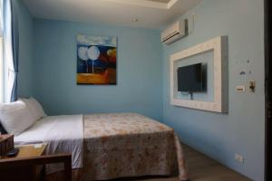 a bedroom with a bed and a tv on the wall at A Cup Hostel in Kenting
