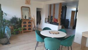 a dining room with a white table and green chairs at Le Relais de Belloy in Belloy sur Somme