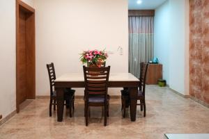 a dining room table with chairs and a vase of flowers at Lotus Resort in Raipur