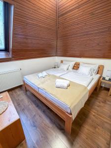 a large bed in a room with wooden walls at Bolla Nyaralóház in Hegyhátszentjakab