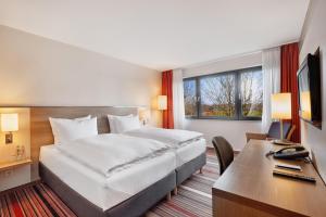 a hotel room with a bed and a desk with a computer at Best Western Hotel Bochum in Bochum