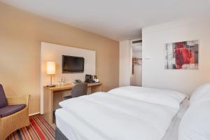 a hotel room with two beds and a desk at Best Western Hotel Bochum in Bochum