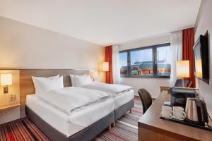 a hotel room with a bed and a desk with a television at Best Western Hotel Bochum in Bochum