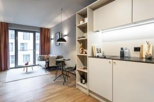 a kitchen with white cabinets and a living room at ipartment Darmstadt HOME by Best Western in Darmstadt