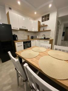 a kitchen with a wooden table and white cabinets at Apartament DeLux WHITE Konin in Konin
