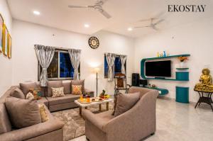 a living room with two couches and a tv at EKOSTAY Gold - Vanamora Villa in Pandhurli