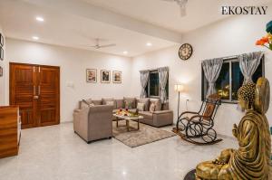 a living room filled with furniture and a clock on the wall at EKOSTAY Gold - Vanamora Villa in Pandhurli