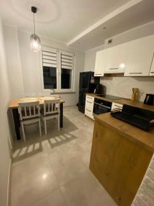 a kitchen with white cabinets and a table and a dining room at Apartament DeLux WHITE Konin in Konin