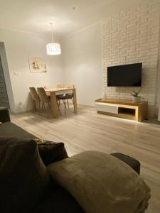 a living room with a tv and a table with chairs at Apartament DeLux WHITE Konin in Konin