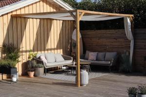 a pergola with a couch and a table on a deck at Villa med Pool in Stockholm