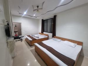 a room with two beds and a television in it at Godavari Lodge in Solapur