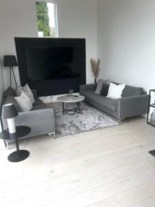 a living room with a couch and a tv at Villa med Pool in Stockholm