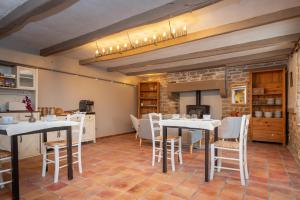 a kitchen and dining room with white tables and chairs at Ty Kerouannec in Guilligomarcʼh