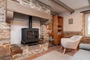 a living room with a stone fireplace and a chair at Ty Kerouannec in Guilligomarcʼh