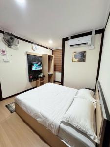 a bedroom with a large bed and a tv at Rumah Kebun Gucher in Kuala Terengganu