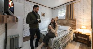 a man standing next to a woman sitting on a bed at Villa Belle Chalés in Campos do Jordão