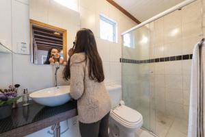 a woman taking a picture of herself in a bathroom at Villa Belle Chalés in Campos do Jordão