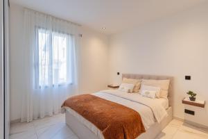 a white bedroom with a large bed and a window at Villa belle rive RdC 3 chambres in Sévrier