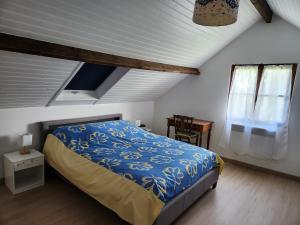 a bedroom with a bed with a blue comforter and a window at Côté Plage in Saint-Marcouf