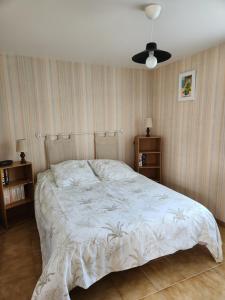 a bedroom with a bed with a white comforter at Côté Plage in Saint-Marcouf