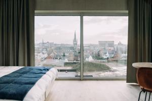 a bedroom with a large window with a view of a city at De Hoorn in Leuven