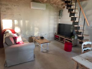 a living room with a couch and a tv and a table at Le Chai d'Auguste in Pauilhac