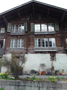 an old wooden house with windows and potted plants at DesAlpes in Saxeten